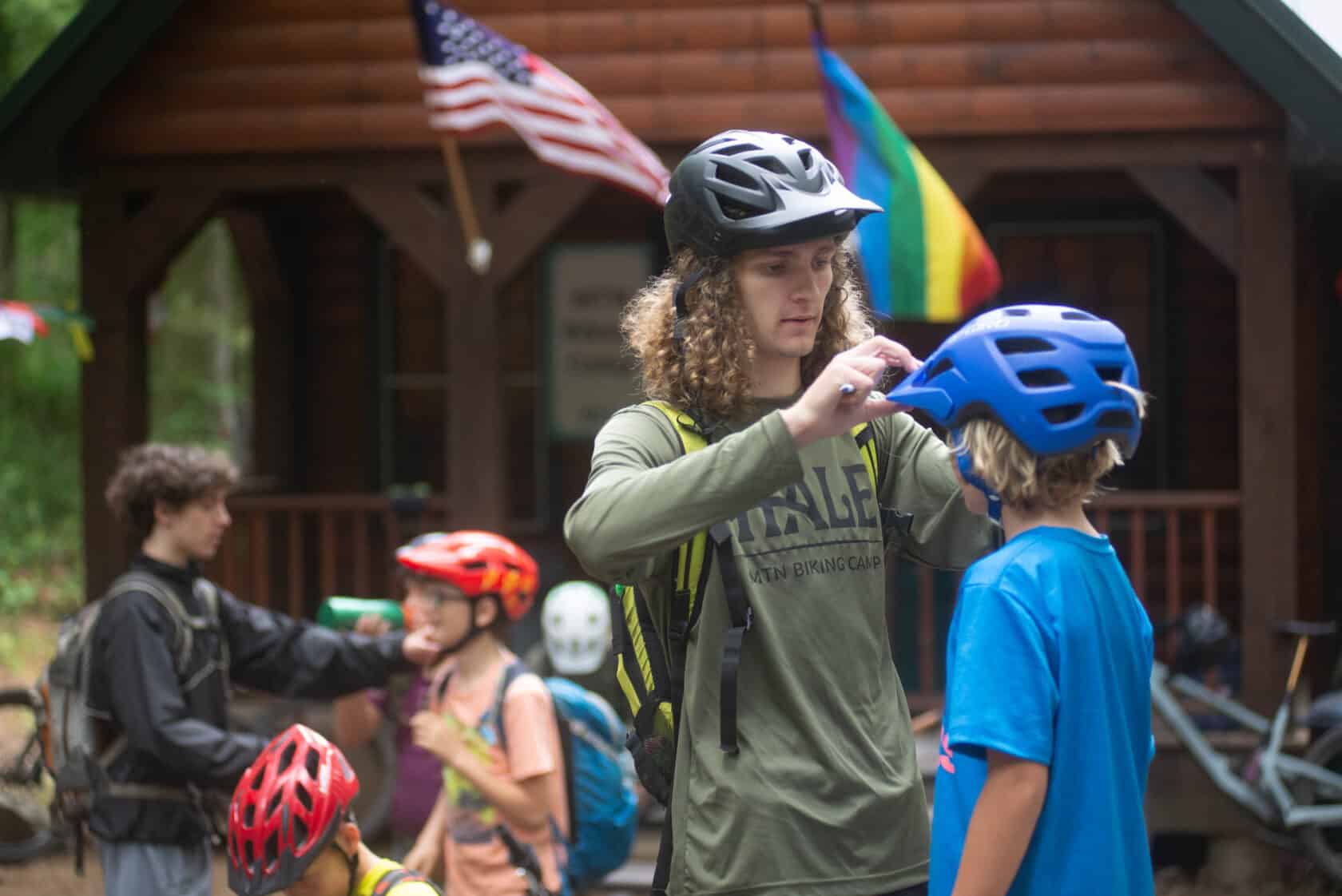 Counselor adjusting bike helmet on camper.