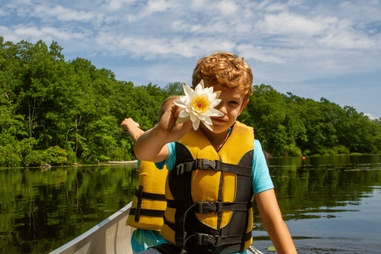 Kid on boat holding up flower.