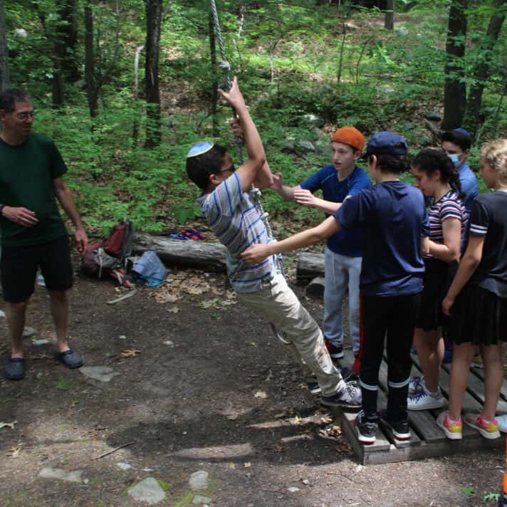 Students help each other on a ropes course.