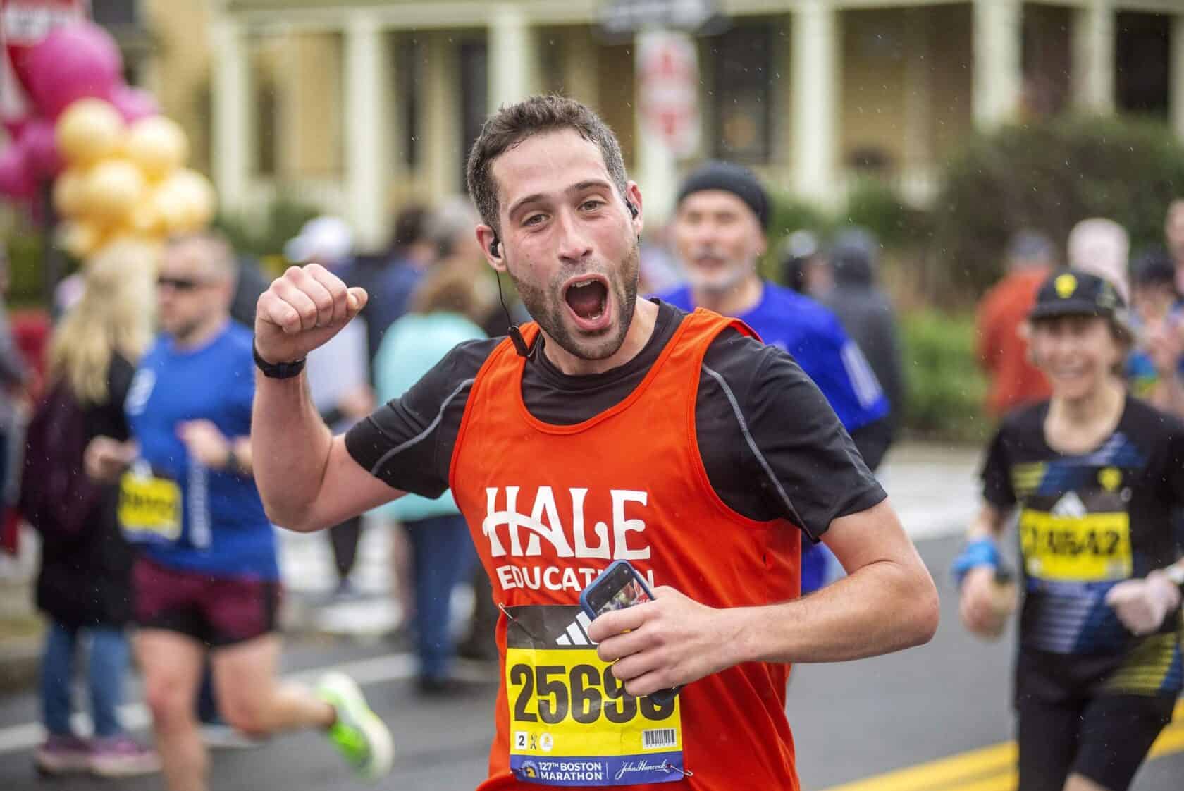 A Boston Marathon runner smiles at spectators as he completes the race