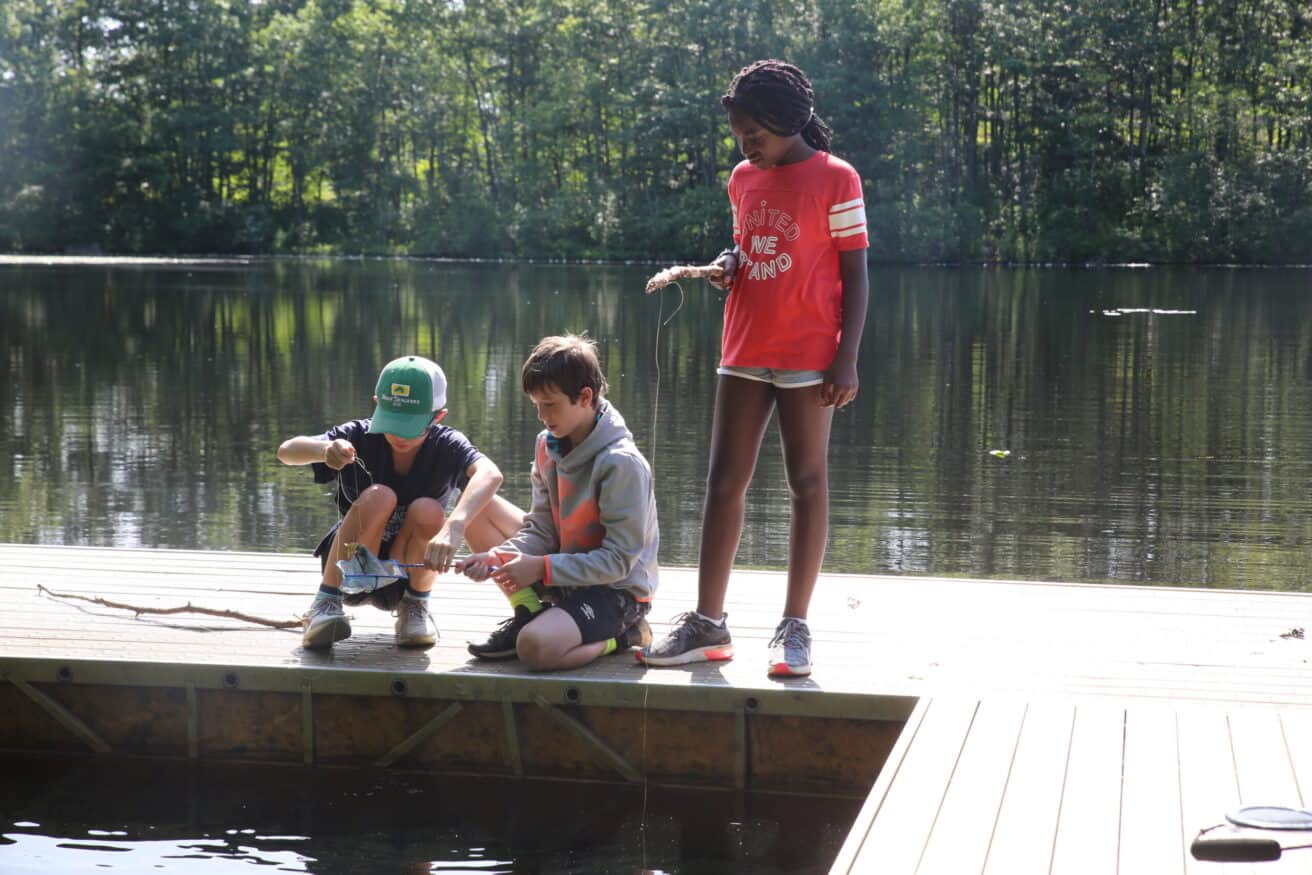 Campers fishing on a lake dock.