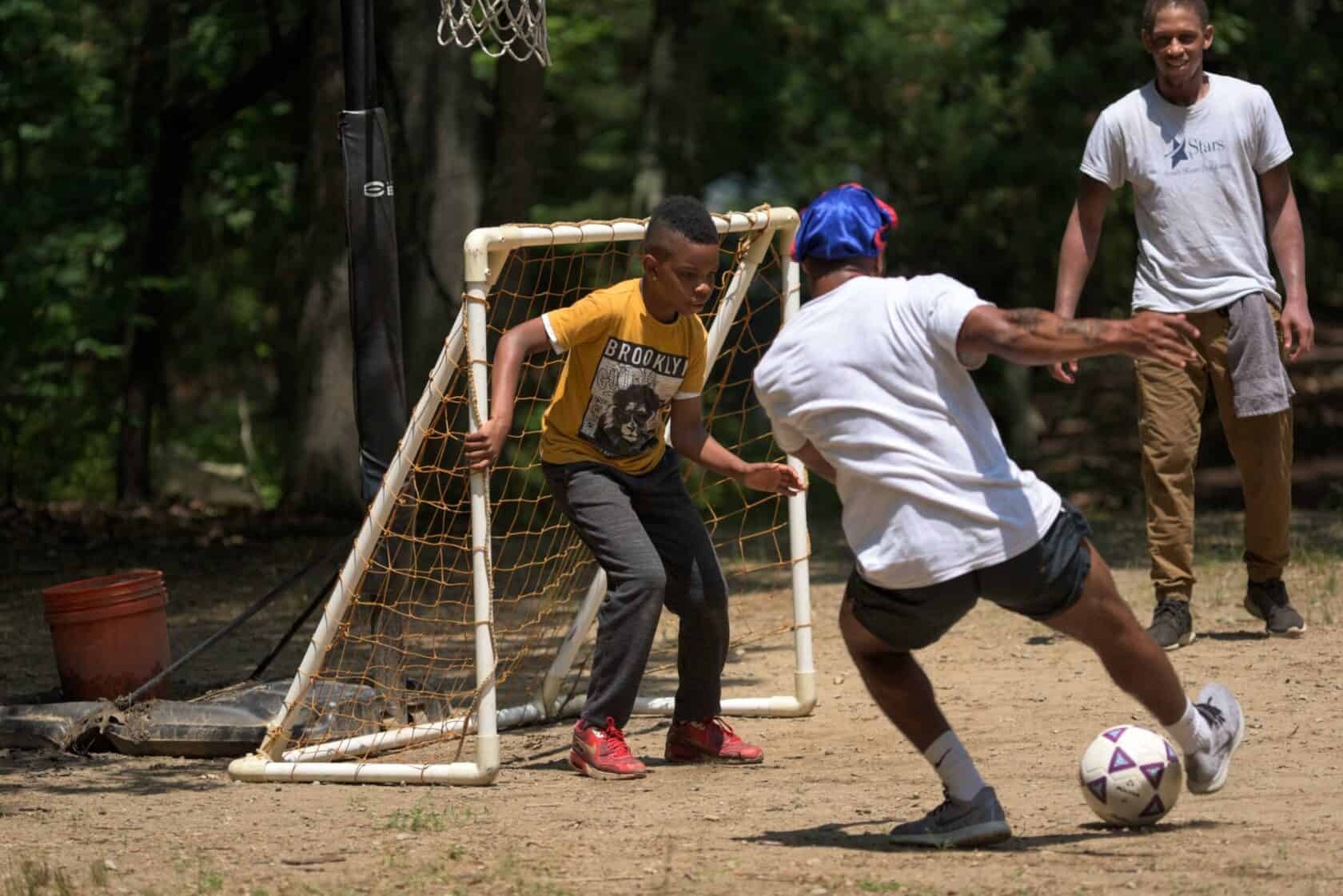 Camper and counselors playing soccer at camp