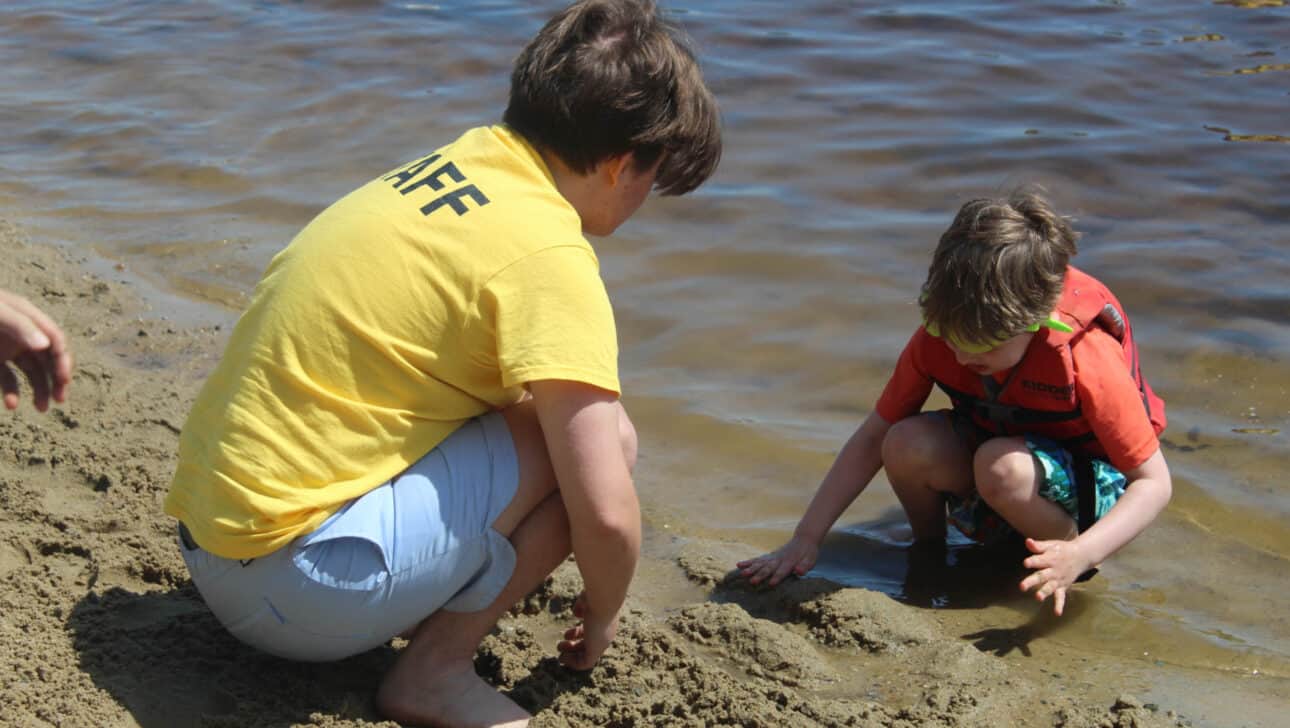 Counselor in Training playing with a camper in the sand.