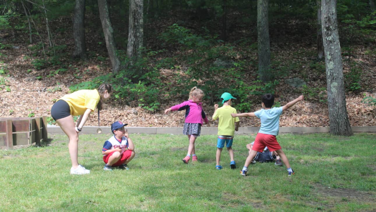Counselor in training playing with campers on a field.