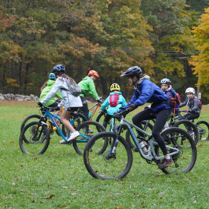 Kids learn to mountain bike in an open field in the fall