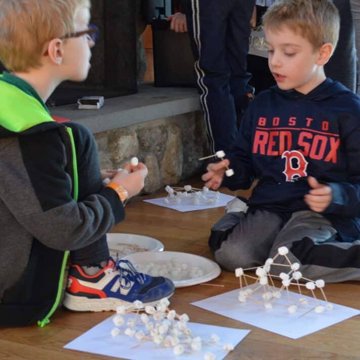 Two students use marshmallows and toothpicks to build a model.