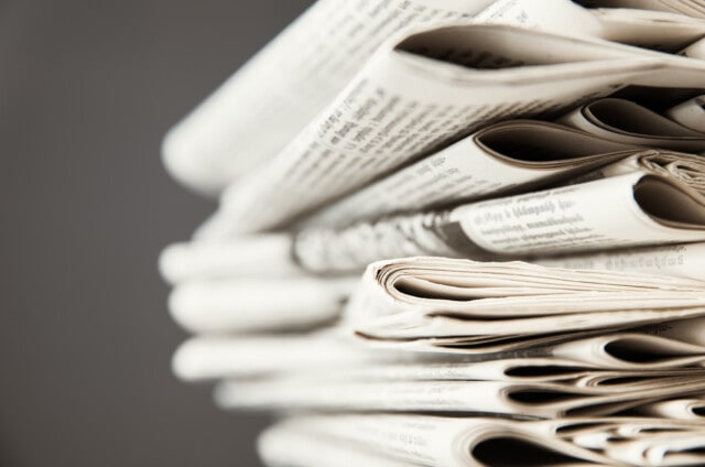 Pile of newspapers on gray background.