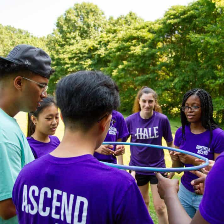 College students use a hula hoop to figure out how to work as a team.