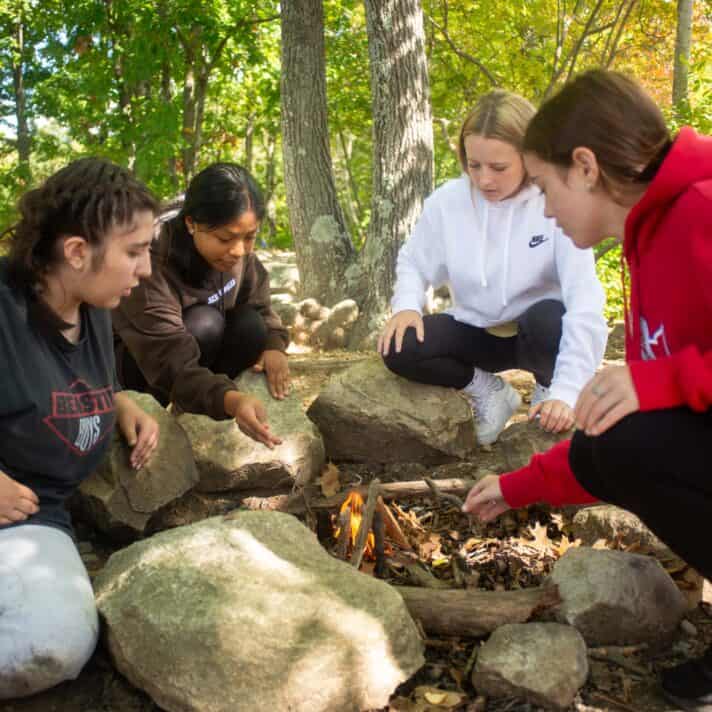 High school students build a fire together in a survival simulation.
