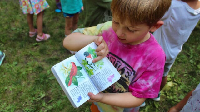 Camper pointing to a page in a book of birds.
