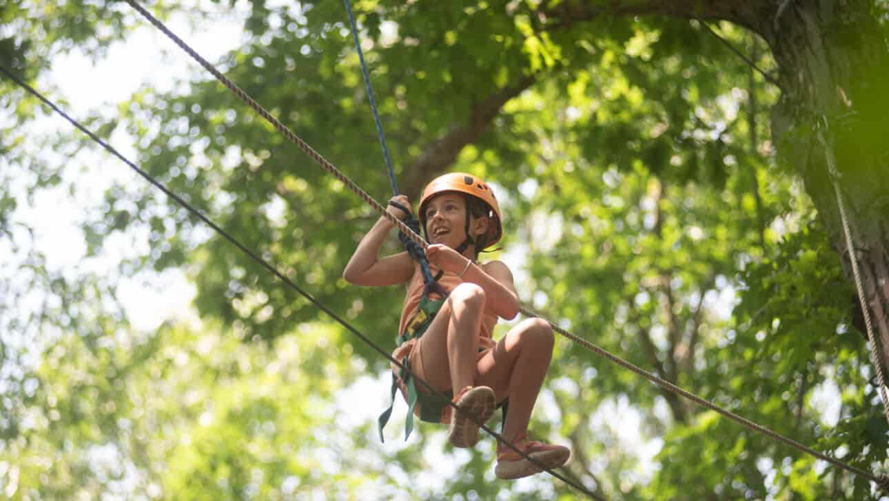 A girl on a zip line in the forest.