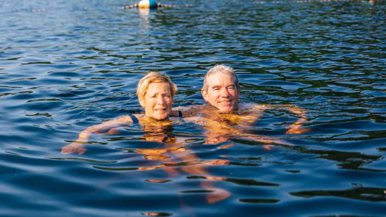 Two older adults swimming in the lake.