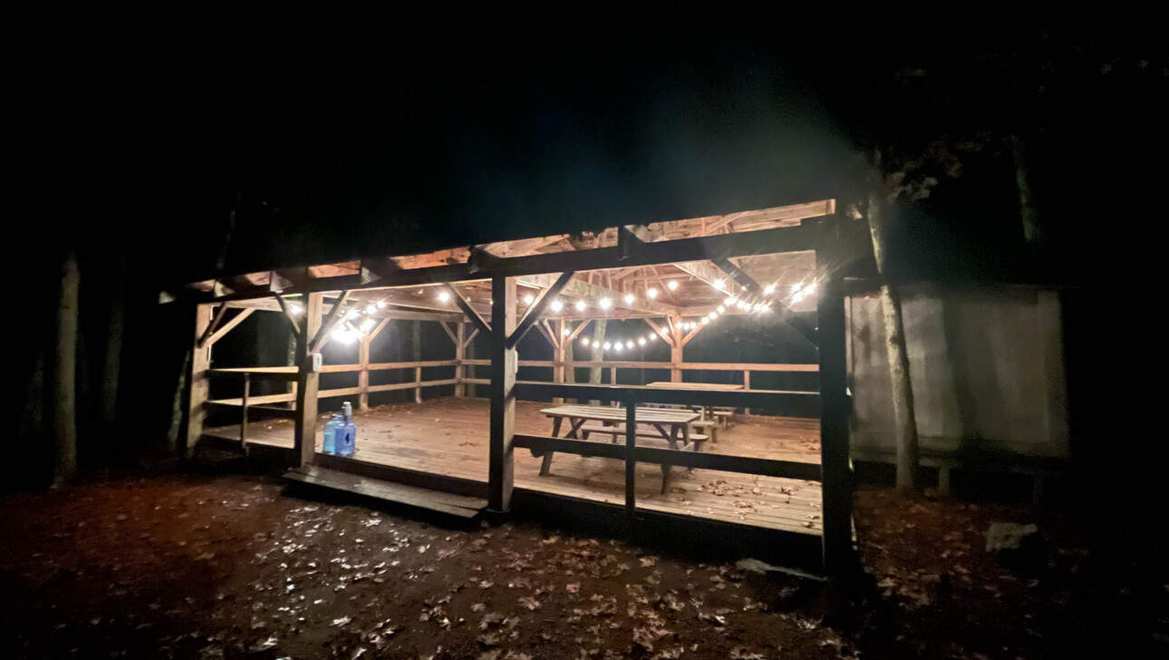 Picnic tables under a structure with string lights.