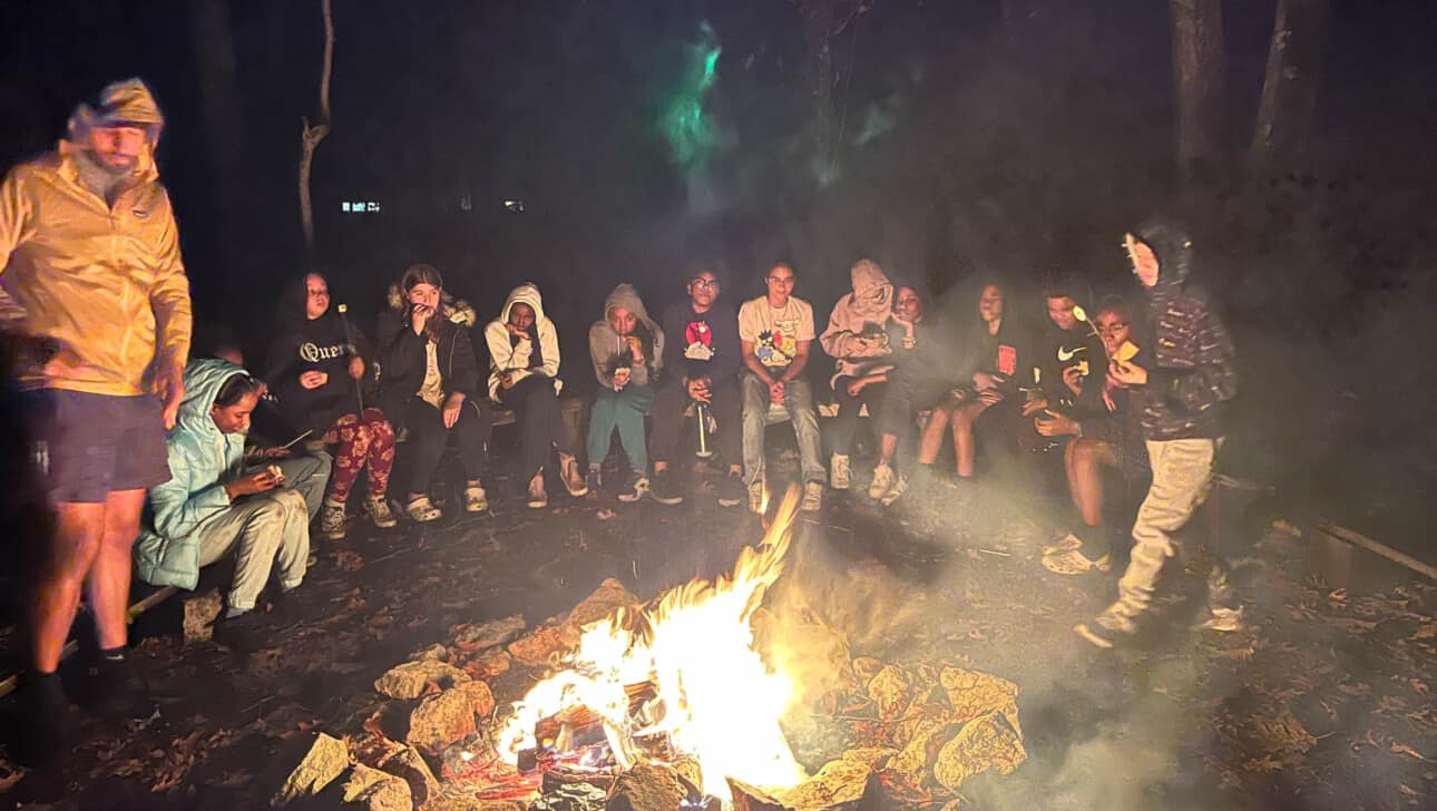 Jeremiah Burke High School’s students sitting around a campfire together.