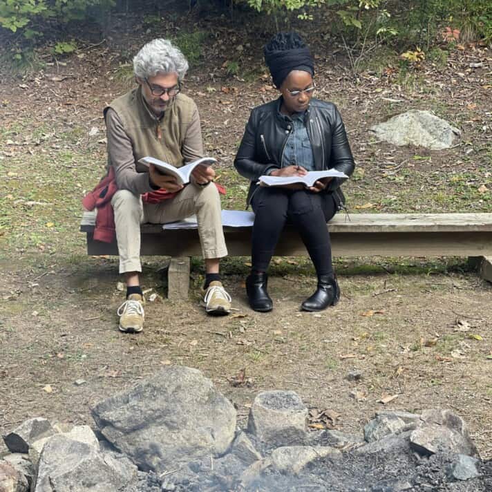 Two adult learners read by a fire
