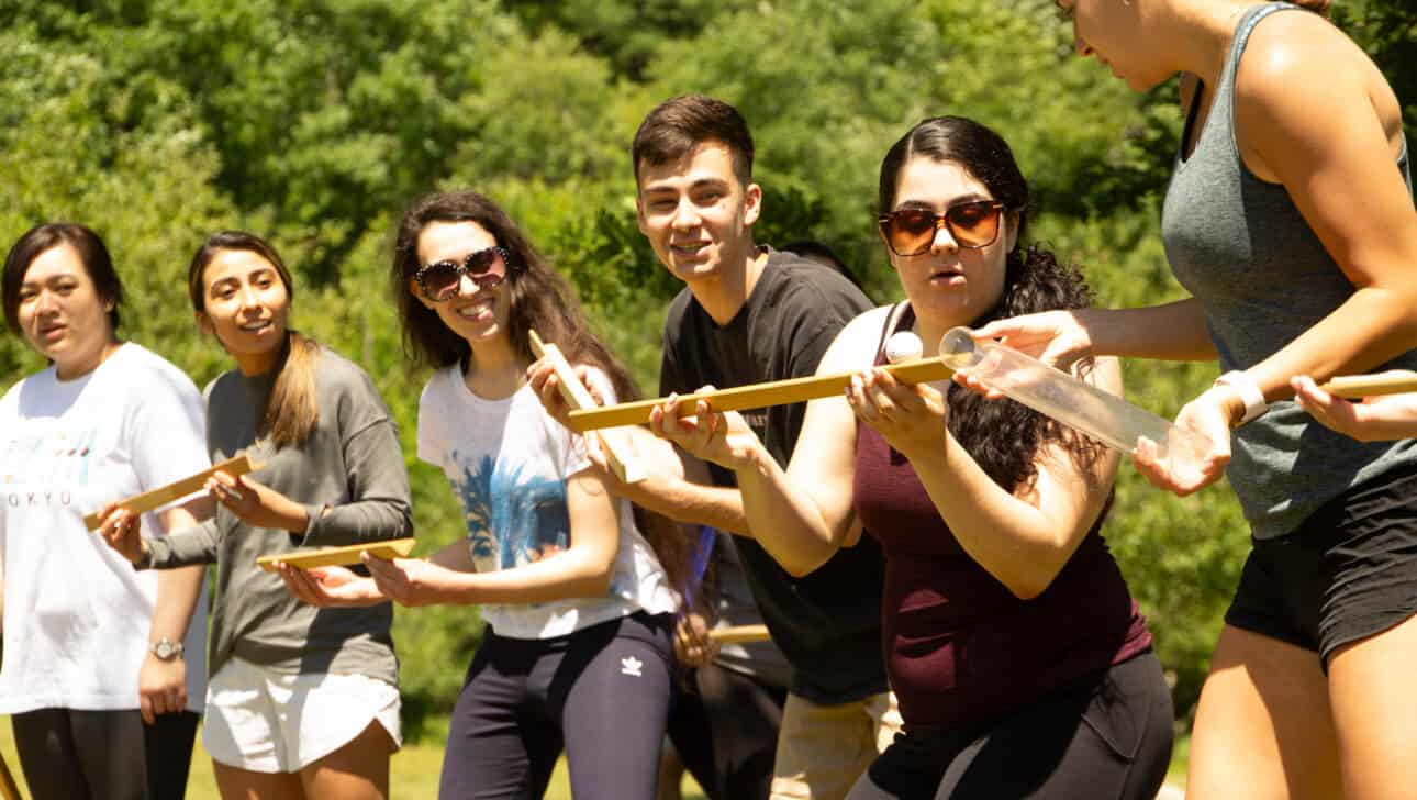 Members from UMass Boston REU program, complete a marble run team building exercise outside.