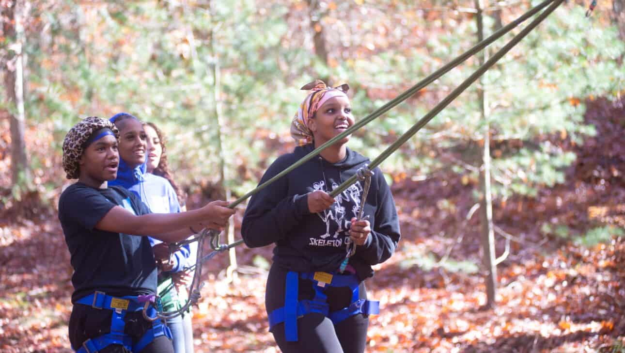 Members from Boston Arts Academy complete a team building exercise outside.