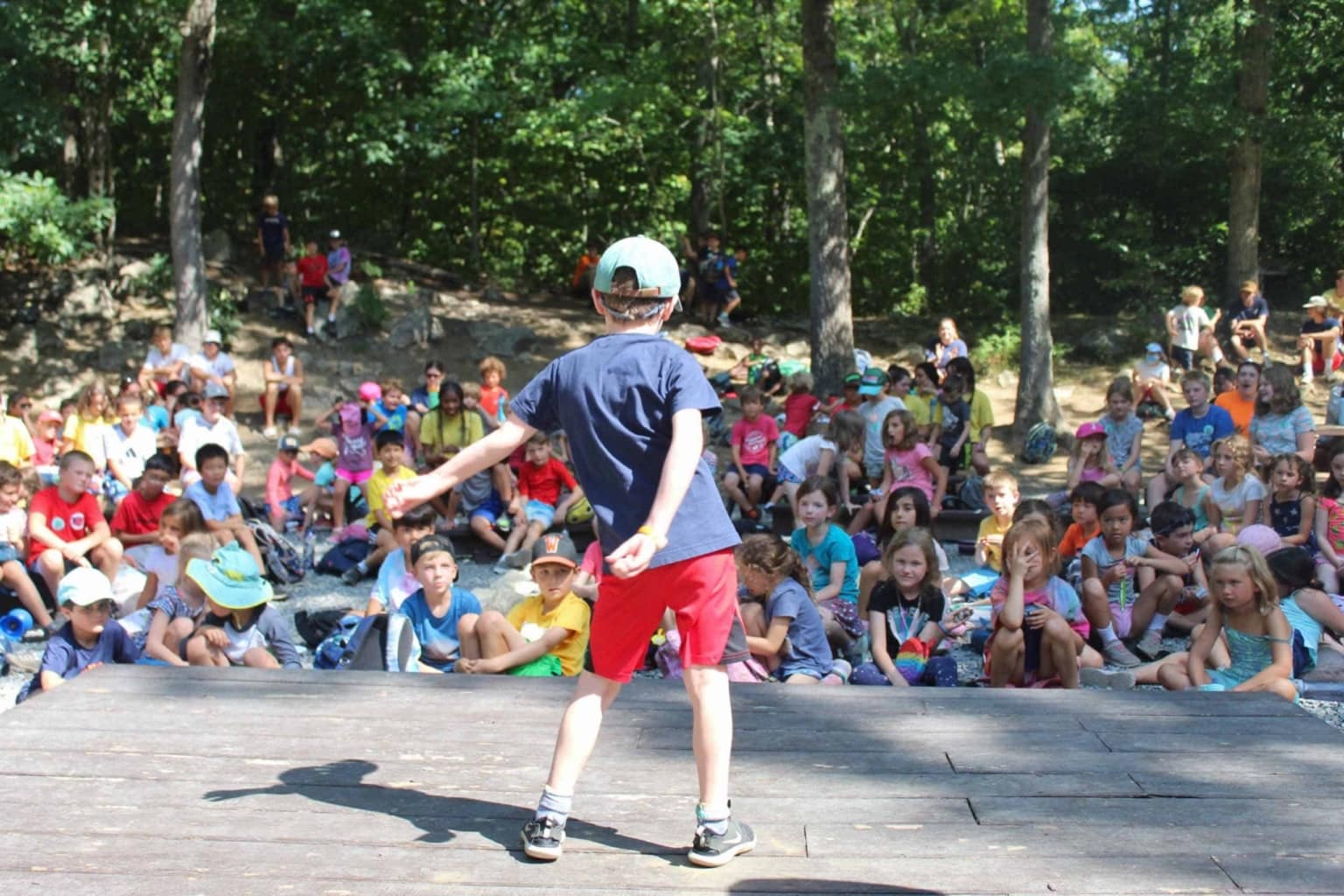 A boy is standing on a stage in front of a crowd of people.