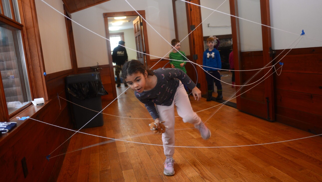 Kids navigate a fake spiderweb during a teambuilding activity