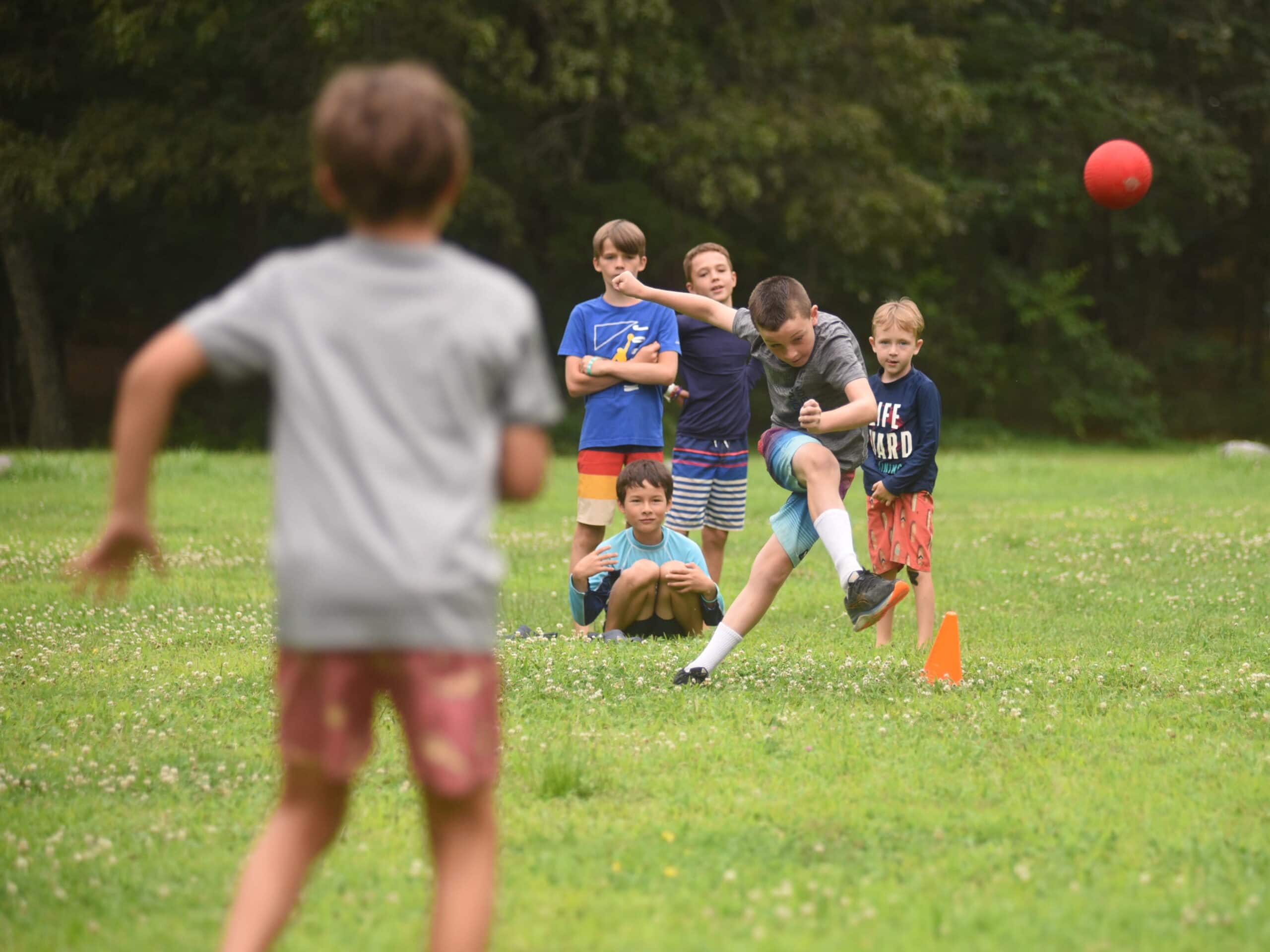 Kids play kickball in a field.