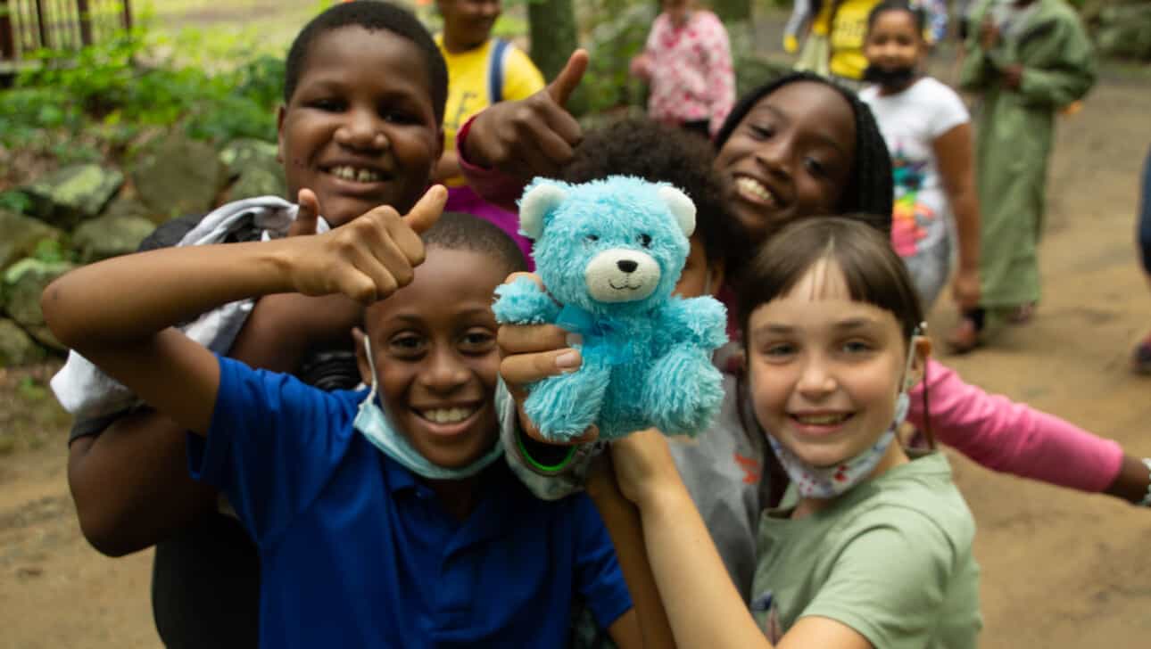 A group of kids holding a teddy bear.