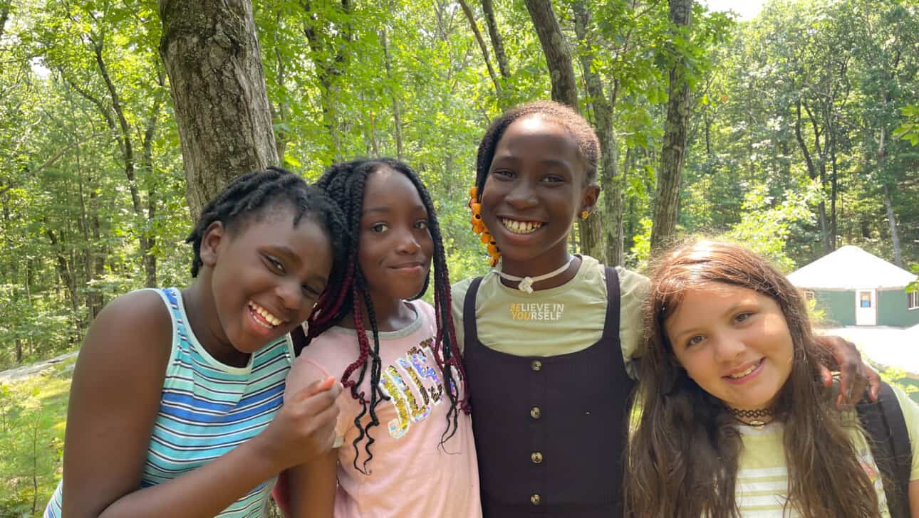 Four girls posing for a picture in the woods.