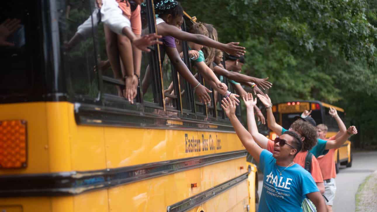 A group of people waving from a school bus.