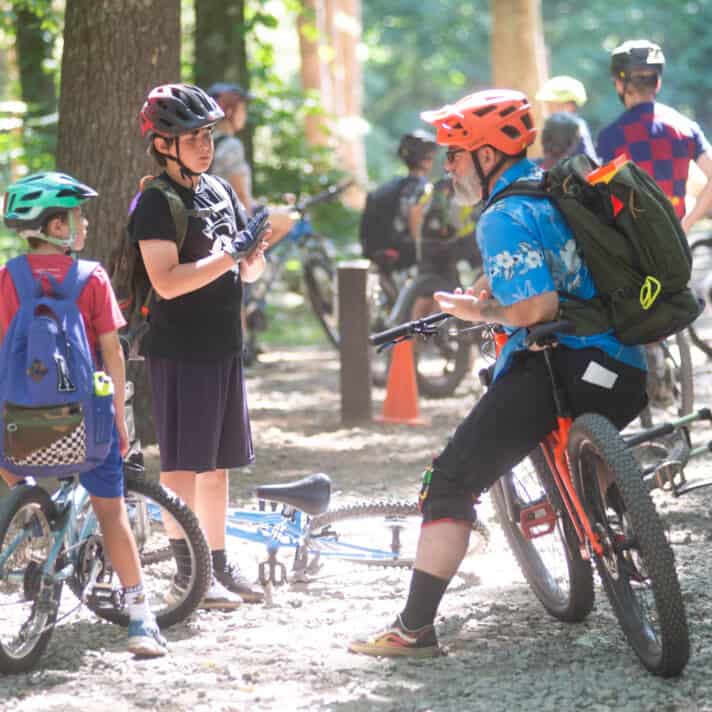 A group of mountain bikers in a wooded area.