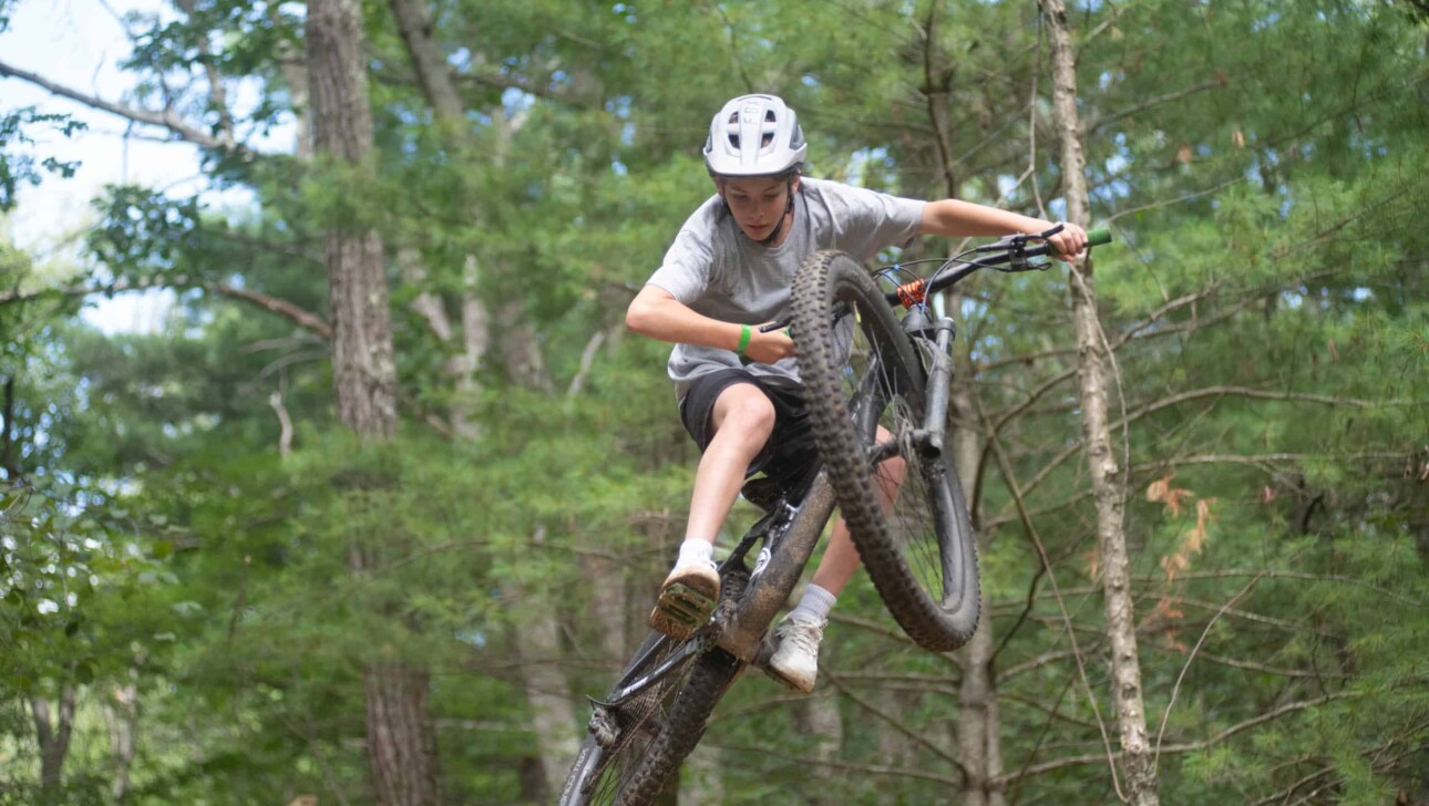 A young man riding a mountain bike in the woods.