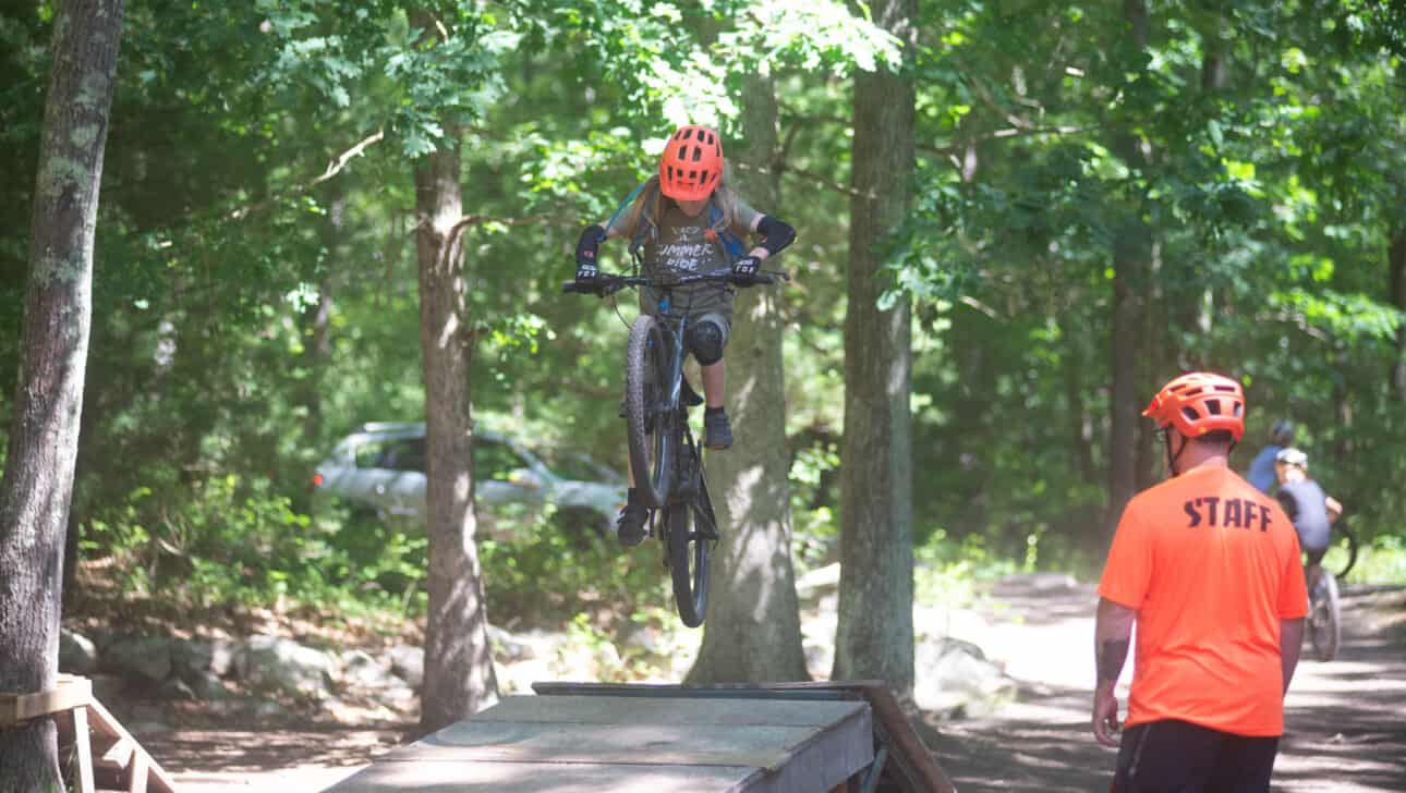 A camper riding a bike on a wooden ramp.