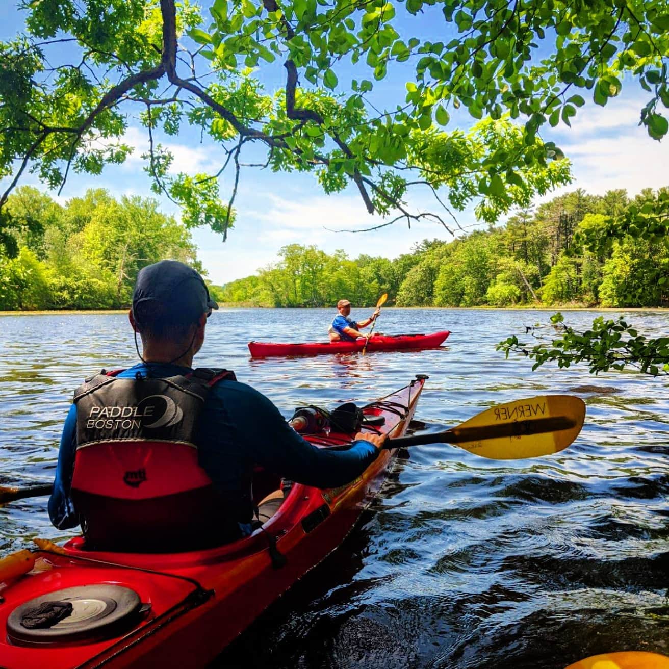A kayaking instructor watches another kayaker paddle by.