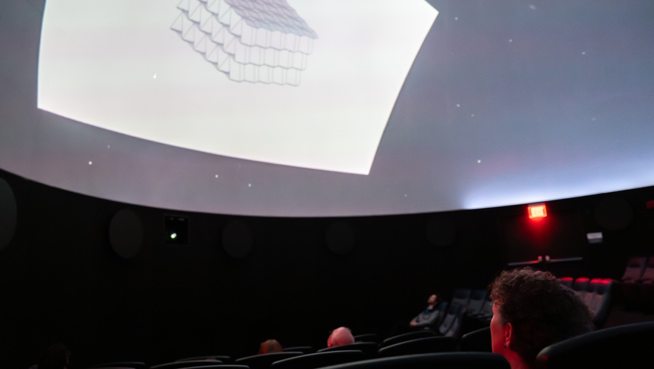 People watch a documentary being projected in a planetarium.
