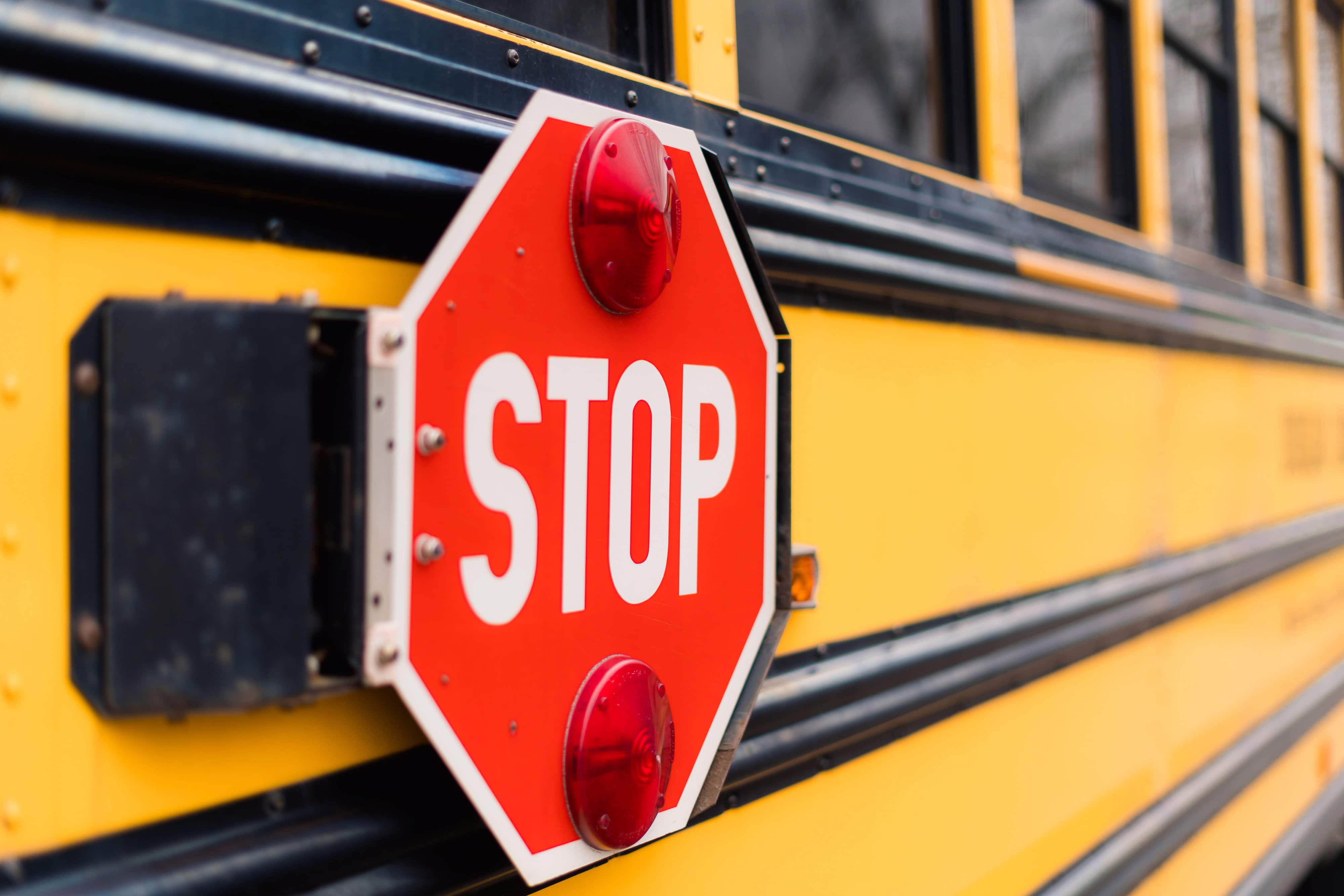 A stop sign on the side of a yellow school bus