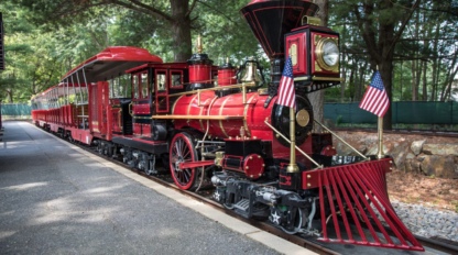 A scale replica of a steam locomotive for children to ride at an outdoor museum.