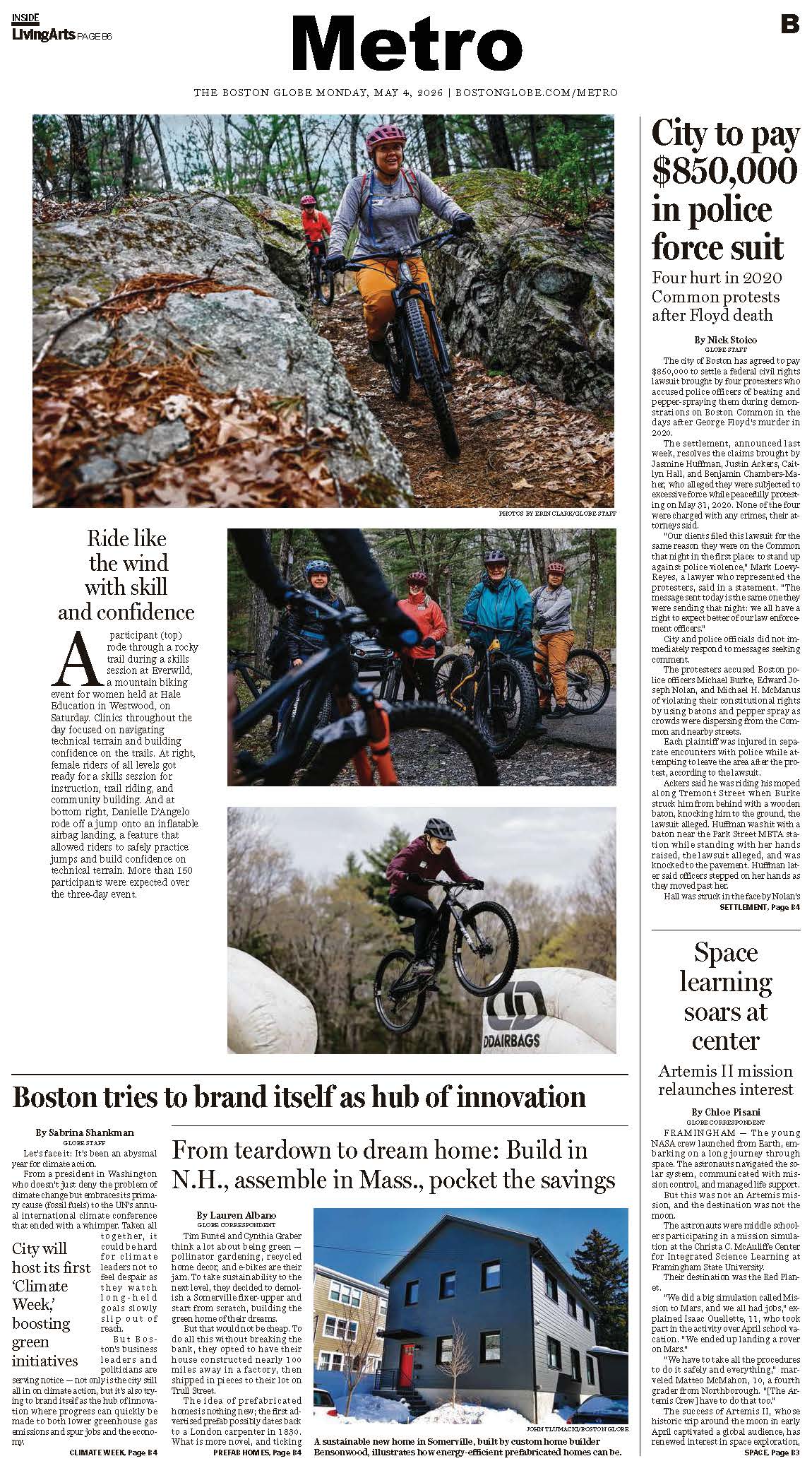 A group of mountain bikers wearing helmets ride along a rocky forest trail; some are navigating over large rocks and tree roots.