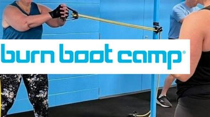 Two women exercise with resistance bands in a fitness studio with blue walls. One woman instructs while the other performs the exercise. "Burn Boot Camp" logo overlays the image.