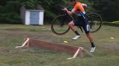 person running over a short jump with a bicycle in his hands