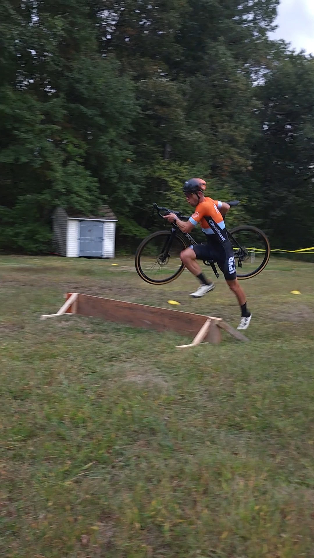 person running over a short jump with a bicycle in his hands